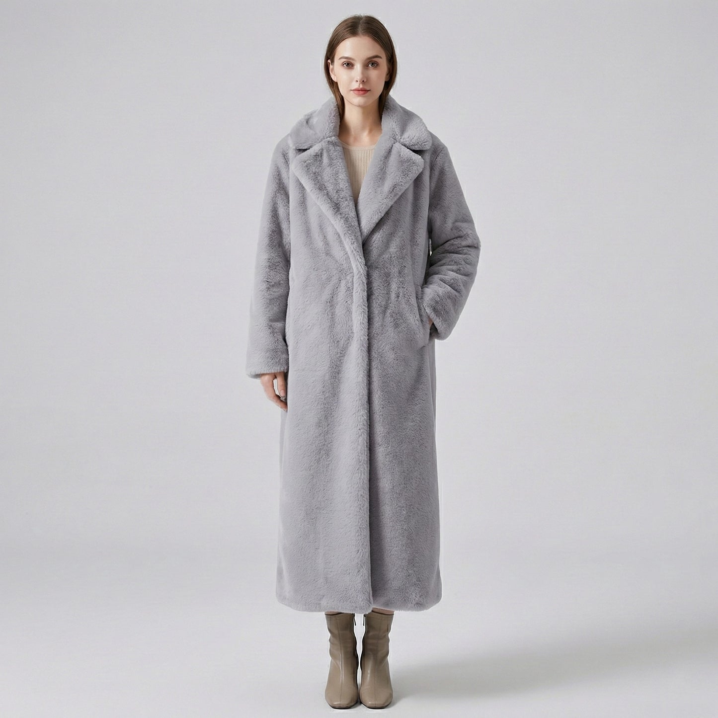 Woman wearing a long gray coat on a plain background