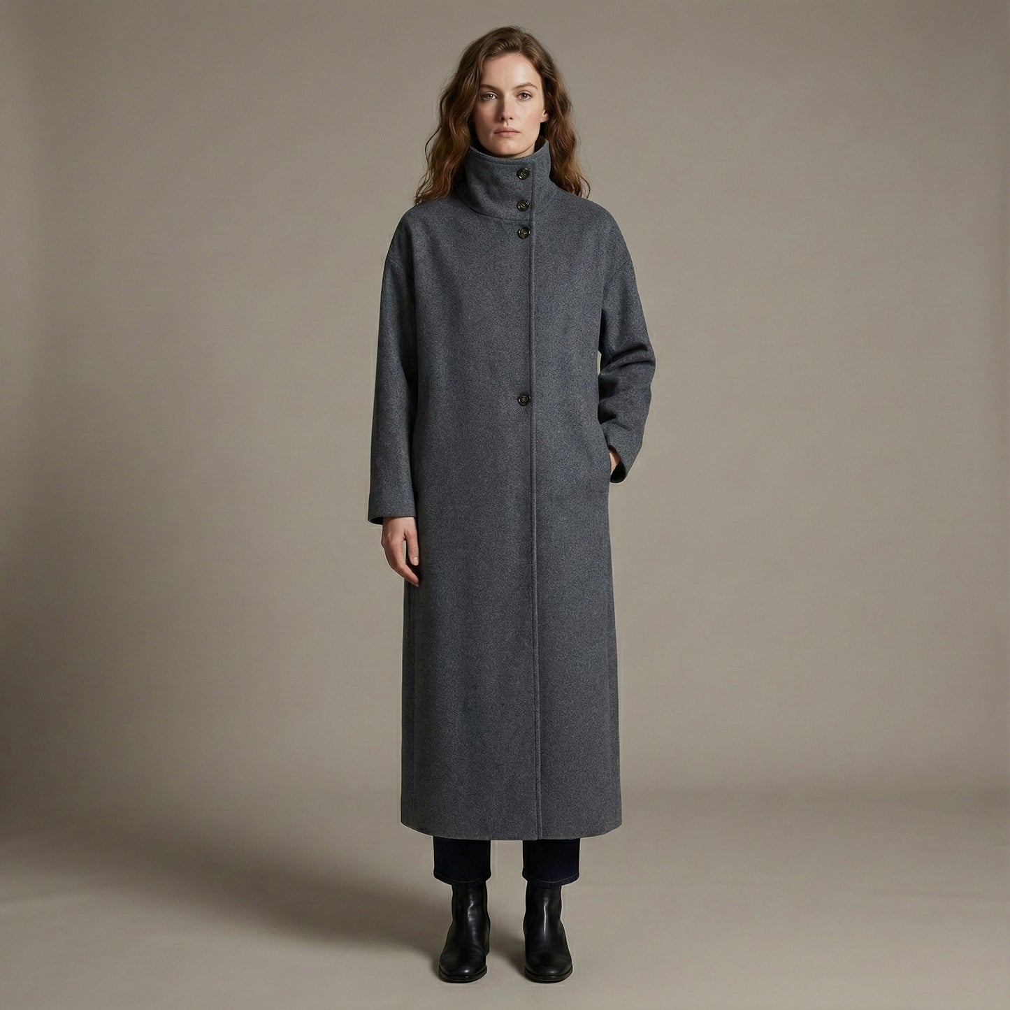 Woman wearing a long gray coat against a plain background