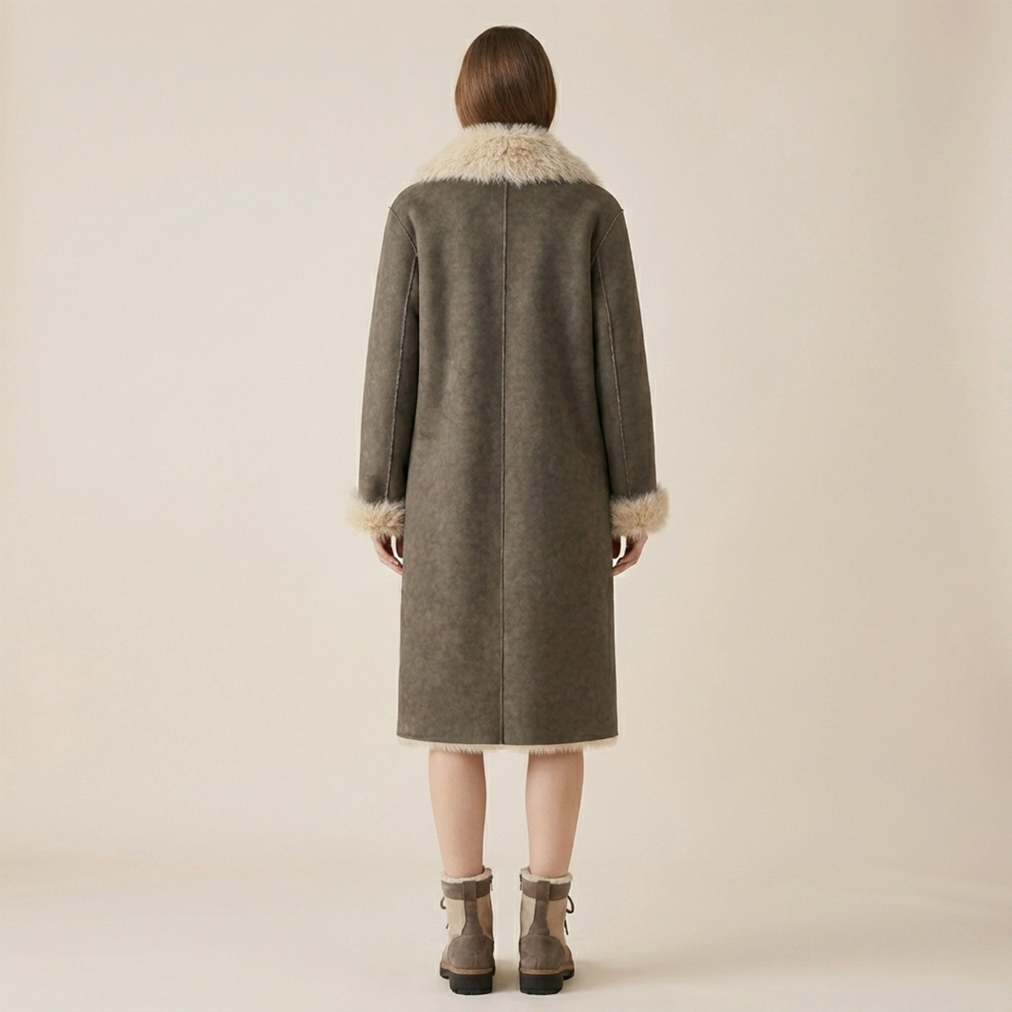 Person wearing a long coat with fur trim on a plain background