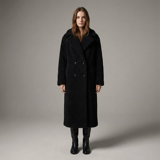 Woman wearing a black coat against a plain background