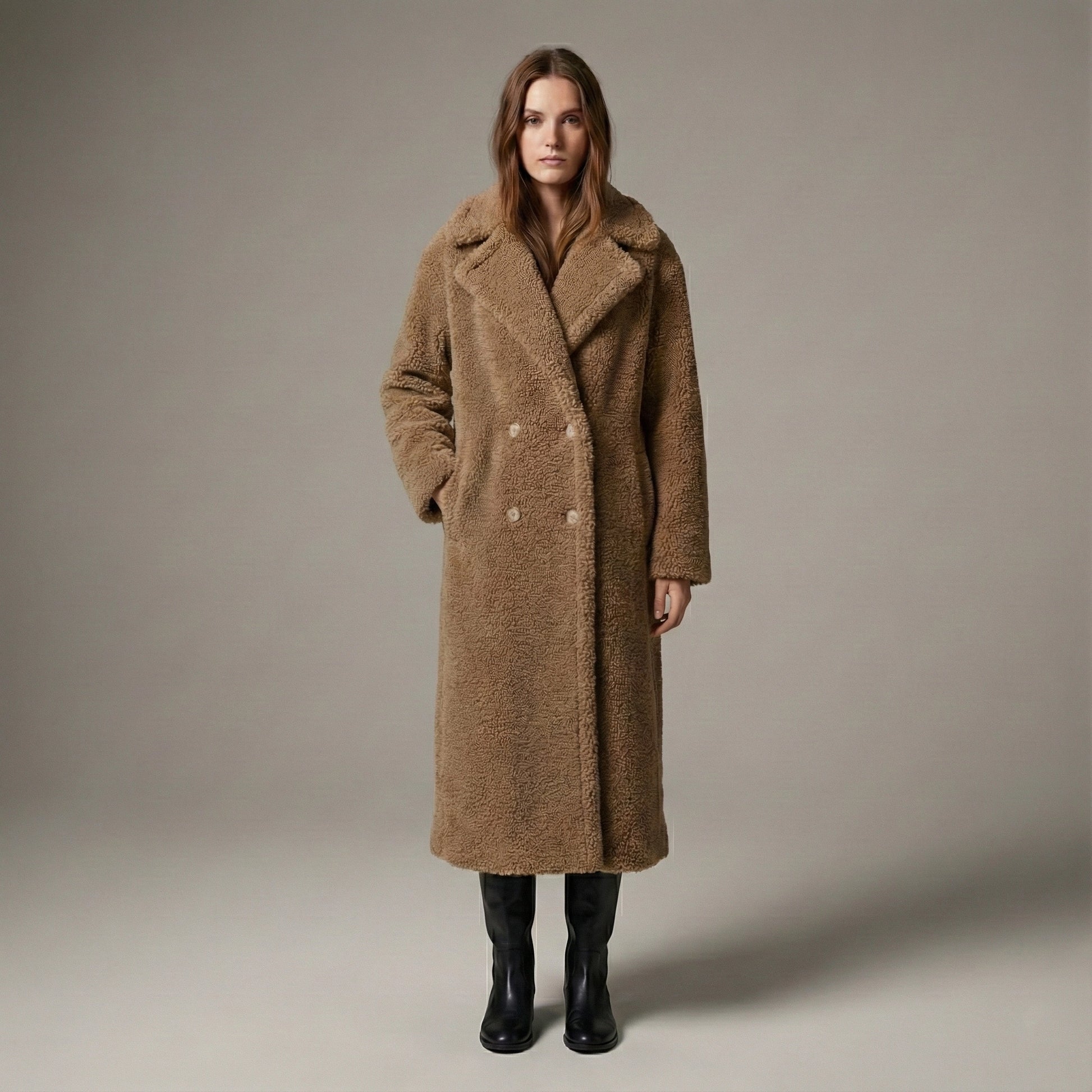Woman wearing a long brown coat against a plain background