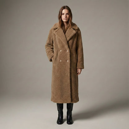 Woman wearing a long brown coat against a plain background
