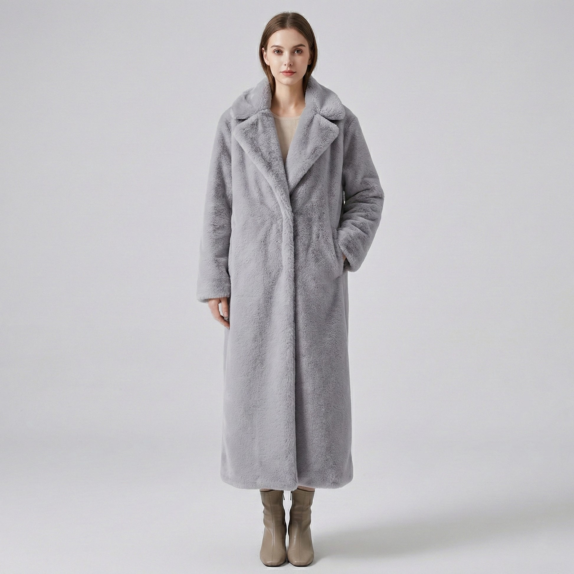 Woman wearing a long gray coat on a plain background