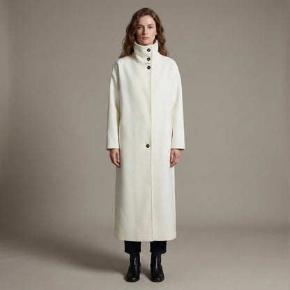 Woman wearing a long white coat against a plain background