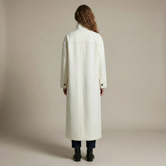 Person wearing a long white coat against a plain background